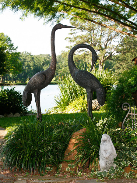 Graceful, life-size crane sculptures complete the lakeside tableau in this South Texas garden.