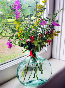 A few final wisps of garden flowers in a simple glass vase light up a windowsill.